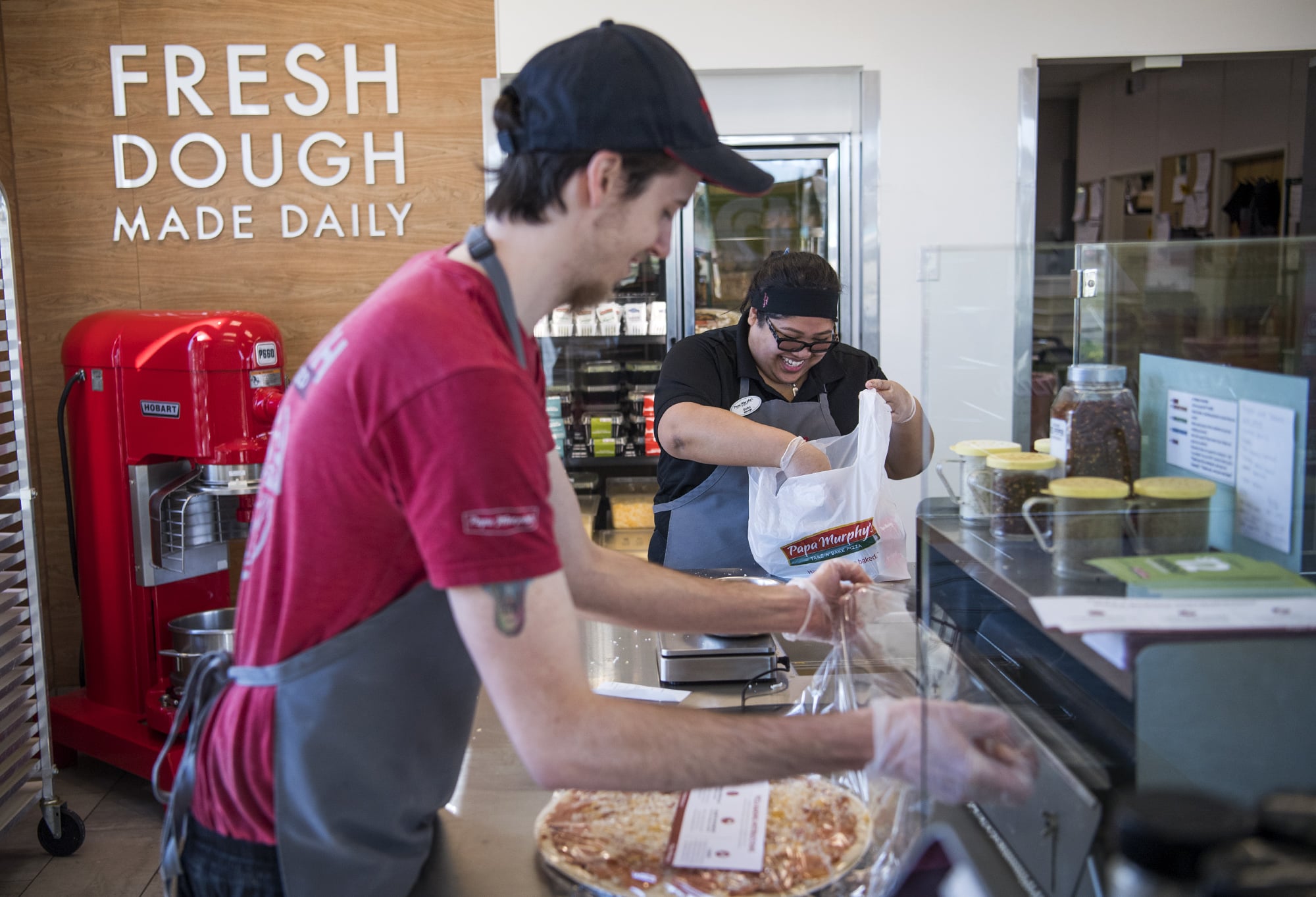 Papa Murphy's employee Chris Ritch, left, and manager Gladys Marron, right, prepare an order at the store on Southeast Mill Plain Boulevard in Vancouver. The Vancouver-based, take-and-bake pizza chain has been bought by the parent company of Pinkberry.