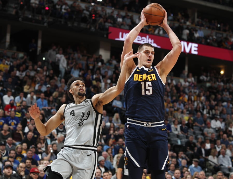 Denver Nuggets center Nikola Jokic, right, pulls in a rebound as San Antonio Spurs guard Derrick White defends in the first half of Game 7 of an NBA basketball first-round playoff series Saturday, April 27, 2019, in Denver.