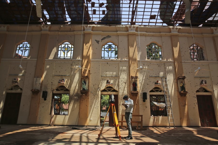 In this Thursday, April 25, 2019 photo, sunlight steams in from gaping holes, as a surveyor works at St. Sebastian’s Church, where a suicide bomber blew himself up on Easter Sunday in Negombo, north of Colombo, Sri Lanka. Nearly a week later, the smell of death is everywhere, though the bodies are long gone. Yet somehow, there’s a beauty to St. Sebastian’s, a neighborhood church in a Catholic enclave north of Sri Lanka’s capital. You can see the beauty in the broken stained-glass windows. It’s there in the little statues that refused to fall over, and despite the swarms of police and soldiers who seem to be everywhere now in the streets of the seaside town of Negombo.