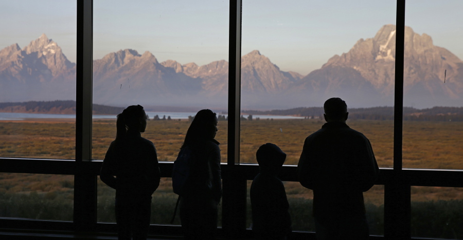 FILE - In this Aug. 28, 2016 file photo, visitors watch the morning sun illuminate the Grand Tetons from within the Great Room at the Jackson Lake Lodge, in Grand Teton National Park, north of Jackson Hole, Wyo. Scientists have completed the most detailed map yet of the geologic fault at the foot of the Teton Range, one of the most visually striking and potentially dangerous seismic areas in North America.