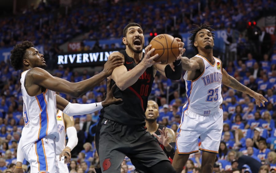 Portland Trail Blazers center Enes Kanter, center, Oklahoma City Thunder forward Jerami Grant, left, and guard Terrance Ferguson, right, compete for a rebound in the second half of Game 4 of an NBA basketball first-round playoff series Sunday, April 21, 2019, in Oklahoma City. Portland won 111-98.