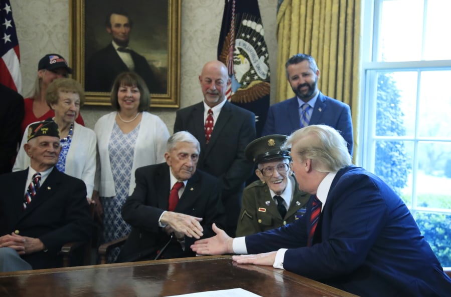 President Donald Trump is joined by World War II veterans, seated from left, Allen Jones, Paul Kriner and Floyd Wigfield on Thursday in the Oval Office.