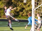 Columbia River's Julian Villa-Salas, left, admires his header over Woodland's Brooks Massey as the ball sails toward Woodland goalkeeper Treyson Thrall, who deflected it into the net. The goal put the Chieftains up 1-0 on the way to 3-0 victory Thursday at Chieftain Stadium in the 2A district championship.