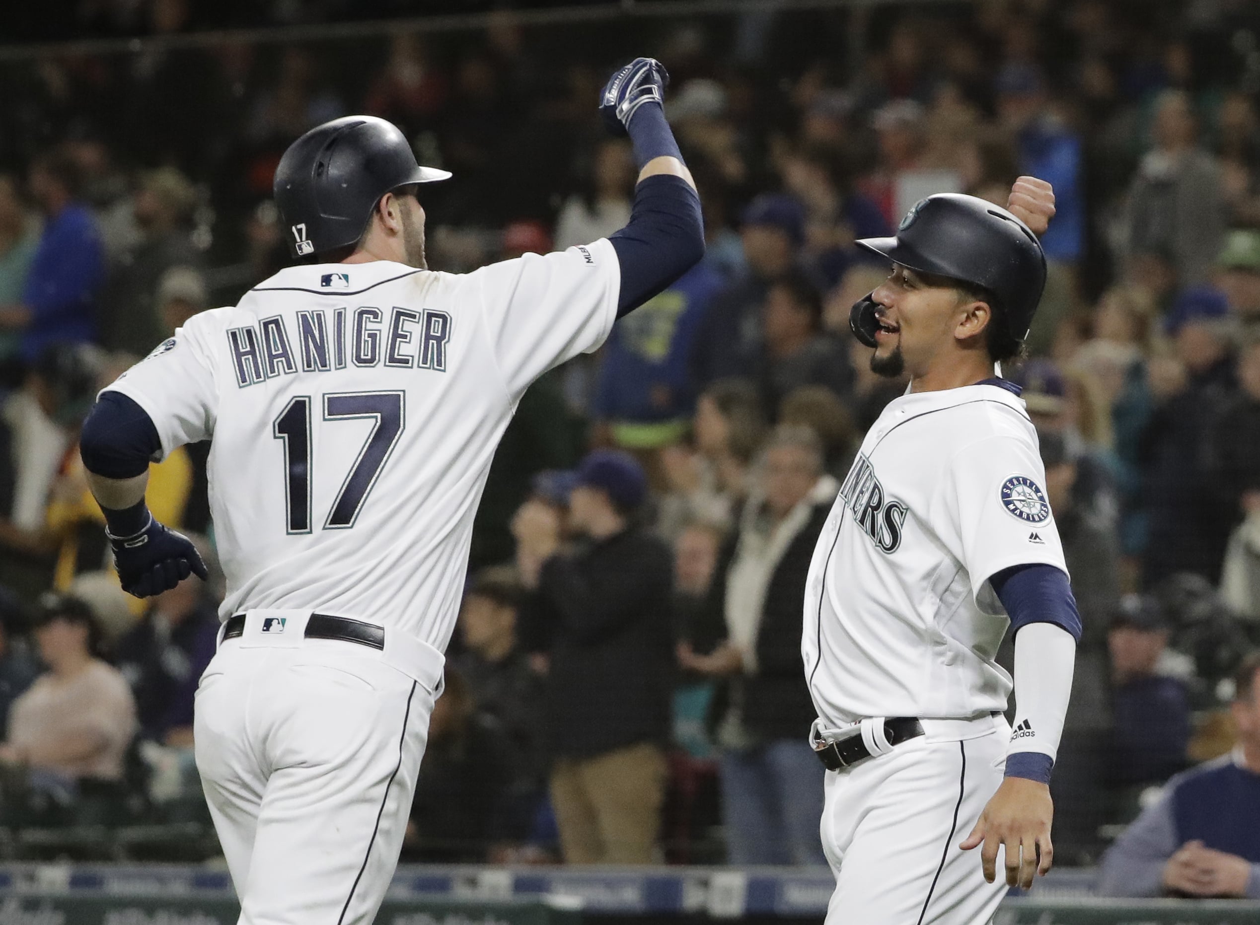 Seattle Mariners' Mitch Haniger is greeted at the dugout by J.P. Crawford after Haniger hit a two-run home run to score Crawford during the fifth inning of the team's baseball game against the Oakland Athletics, Tuesday, May 14, 2019, in Seattle. (AP Photo/Ted S.