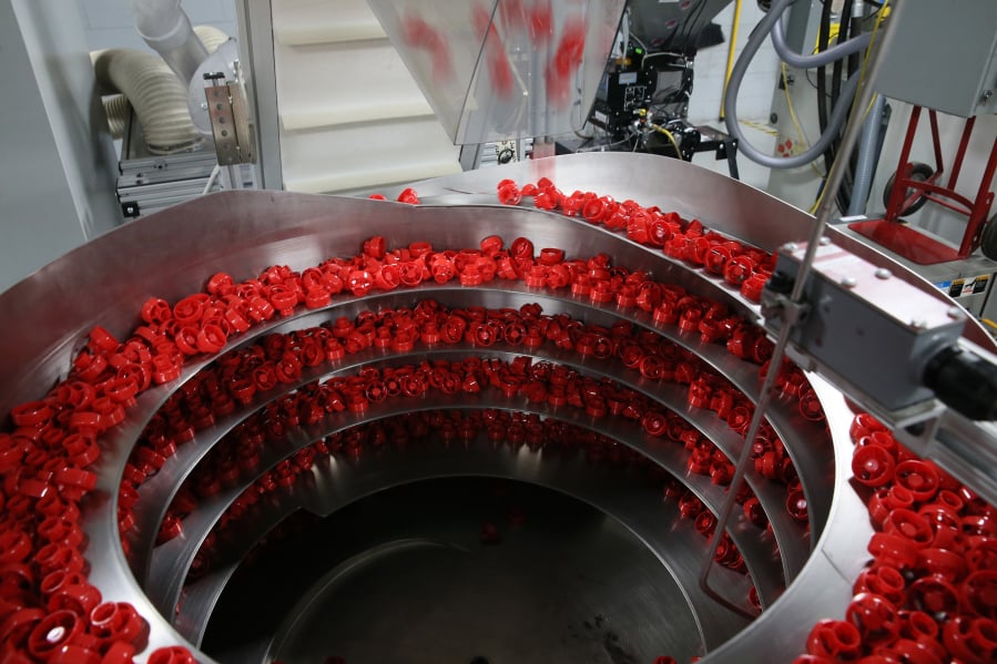 Plastic caps for squeezable pouches swirl around in a machine at Hoffer Plastics on May 13, 2019, in South Elgin.