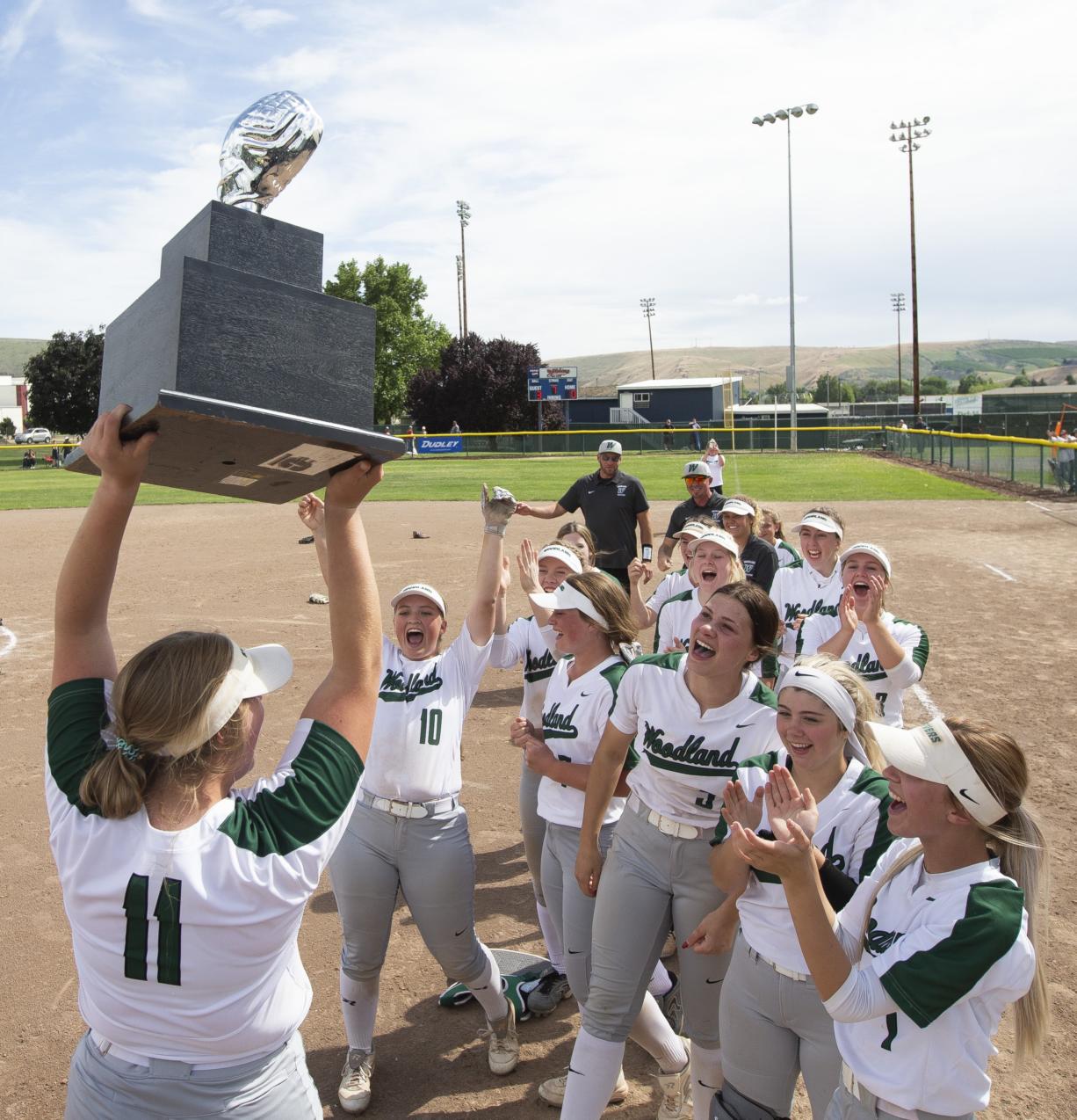Woodland's Olivia Grey holds up the state championship trophy as her teammates celebrate after a 3-0 victory over W.F. West on Saturday, May 25, 2019 at Carlon Park in Selah, Wash.