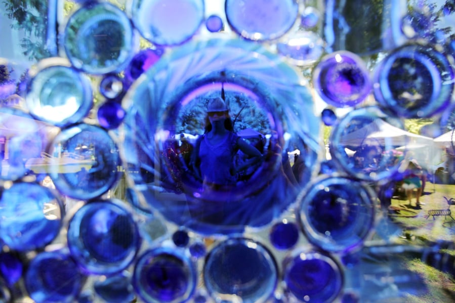 Shopper Dana Slamp is seen through a glass mosaic created by artist Darla Lynn at the annual Recycled Art Fair in Esther Short Park in downtown Vancouver Sunday June 26, 2016. The event hosts veterans for a day of fishing.