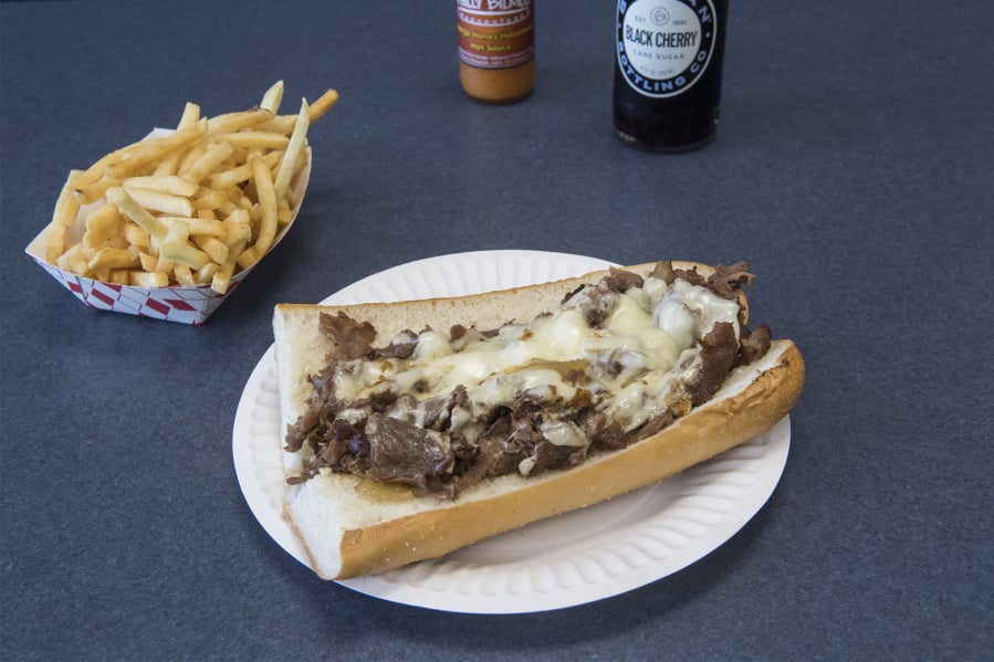 A traditional Philly cheesesteak and fries with Philly Bilmos hot sauce.