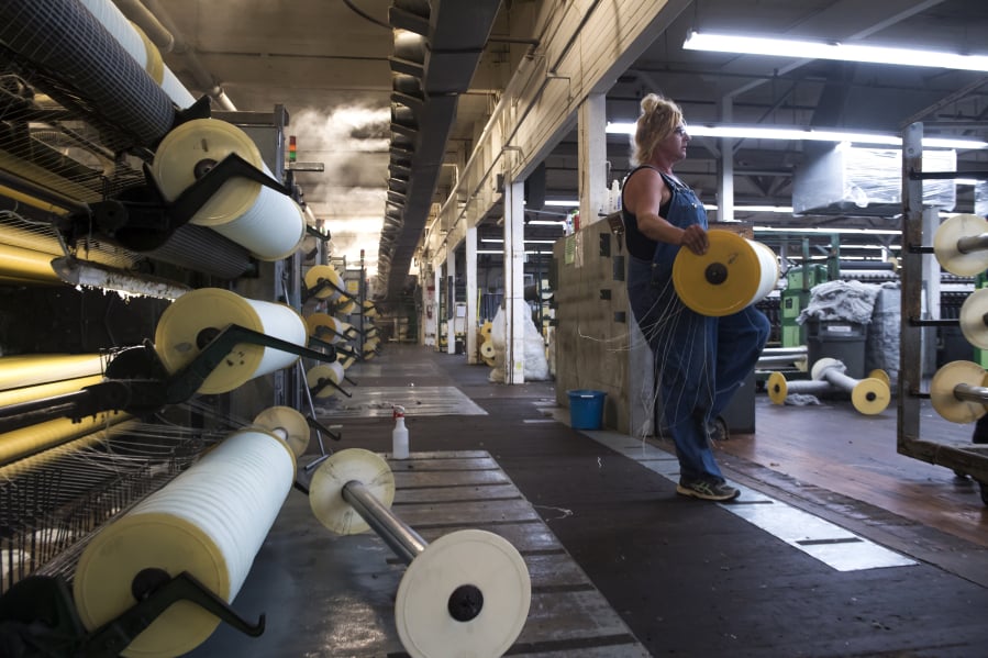 Jill Carroll carries a roll of wool from a carding machine at the Pendleton Washougal Mill.