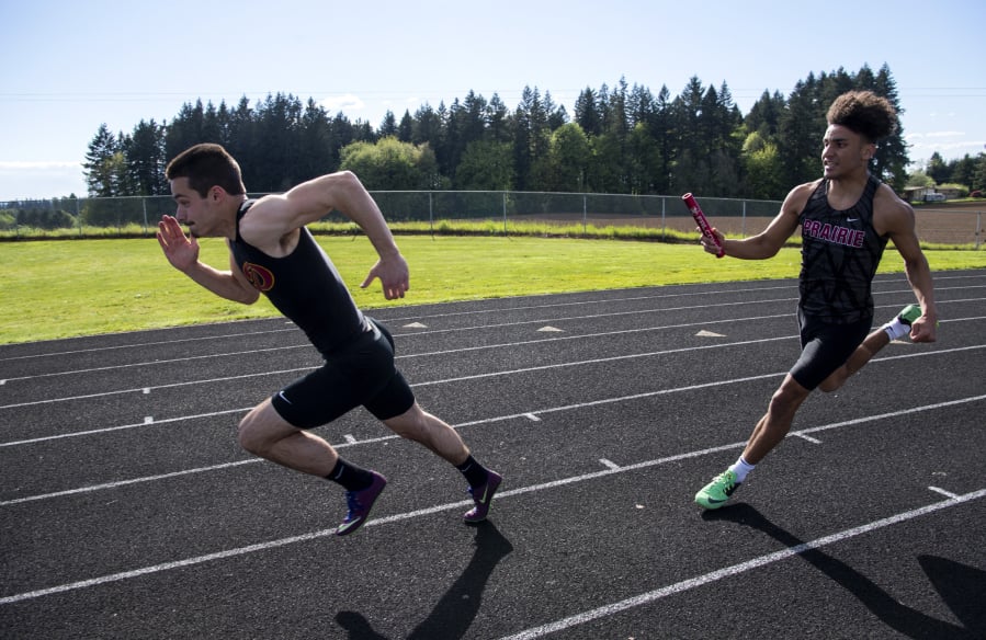 Prairie High School senior Nolan Mickenham, left, takes off as Zeke Dixson hands off to him during the 400-meter relay in Vancouver, Wash., on April 30, 2019.