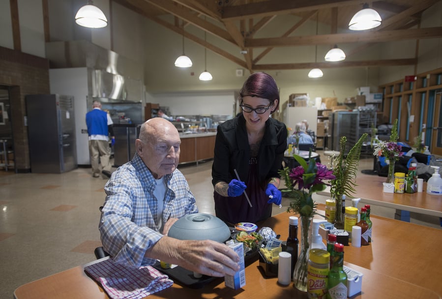 Milt Olsen, a former aviator who served during the Vietnam War, gets a assistance with lunch from Nutrition and Food Services Operations Manager Jenelle Cruz in the Community Living Center’s dining room at VA Portland Health Care System, Vancouver Campus Tuesday afternoon.