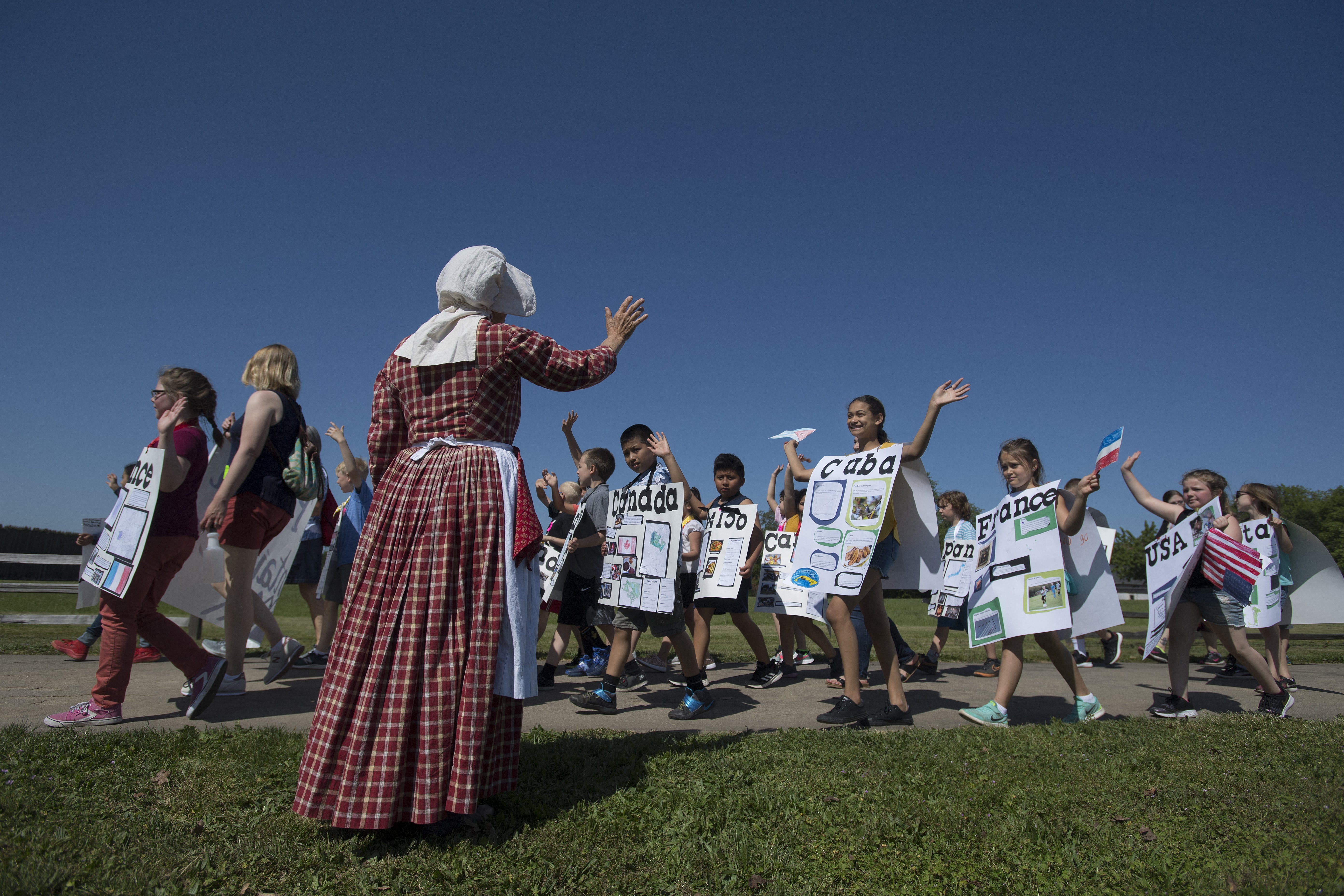 Fort Vancouver National Historic Site volunteer Becky Hudak, in plaid, dressed as a Metis from 1845, gives a warm welcome to students taking part in the annual Children's Cultural Parade as they prepare to enter the stockade Friday morning, May 10, 2019. Over 1,500 third grade students celebrated learning, community and diversity as they marched through the parade route and ended at the stockade with a speech by Gov. Jay Inslee.