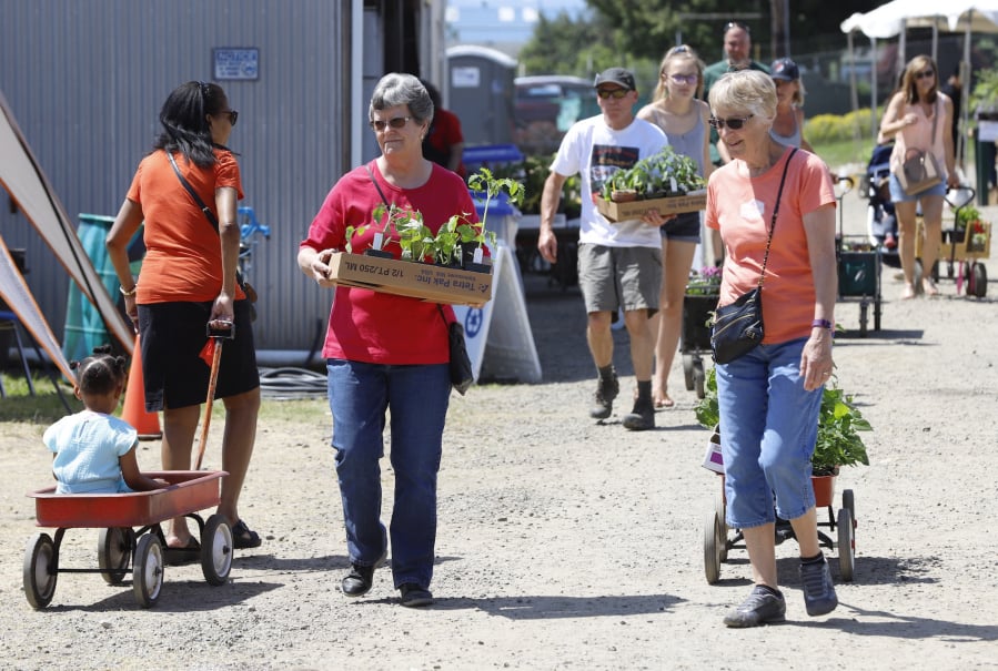 Lura Morrow, left, of Battle Ground and Sharon Handlos, right, of Brush Prairie carry plants they selected at the Master Gardener Foundation of Clark County Mother’s Day Weekend Plant Sale.