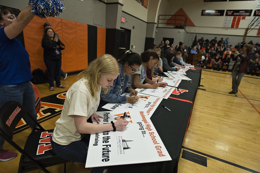 Shelby Jolly, 18, a Washougal High School senior, foreground, signs her name on a poster as she joins fellow classmates in celebrating their post-high school plans. Jolly, who was part of the group heading to Clark College in the fall, took part in Washougal’s first College and Career Signing Day. Students signed lawn signs to announce what college, branch of the military or apprenticeship program they plan to attend after graduating.