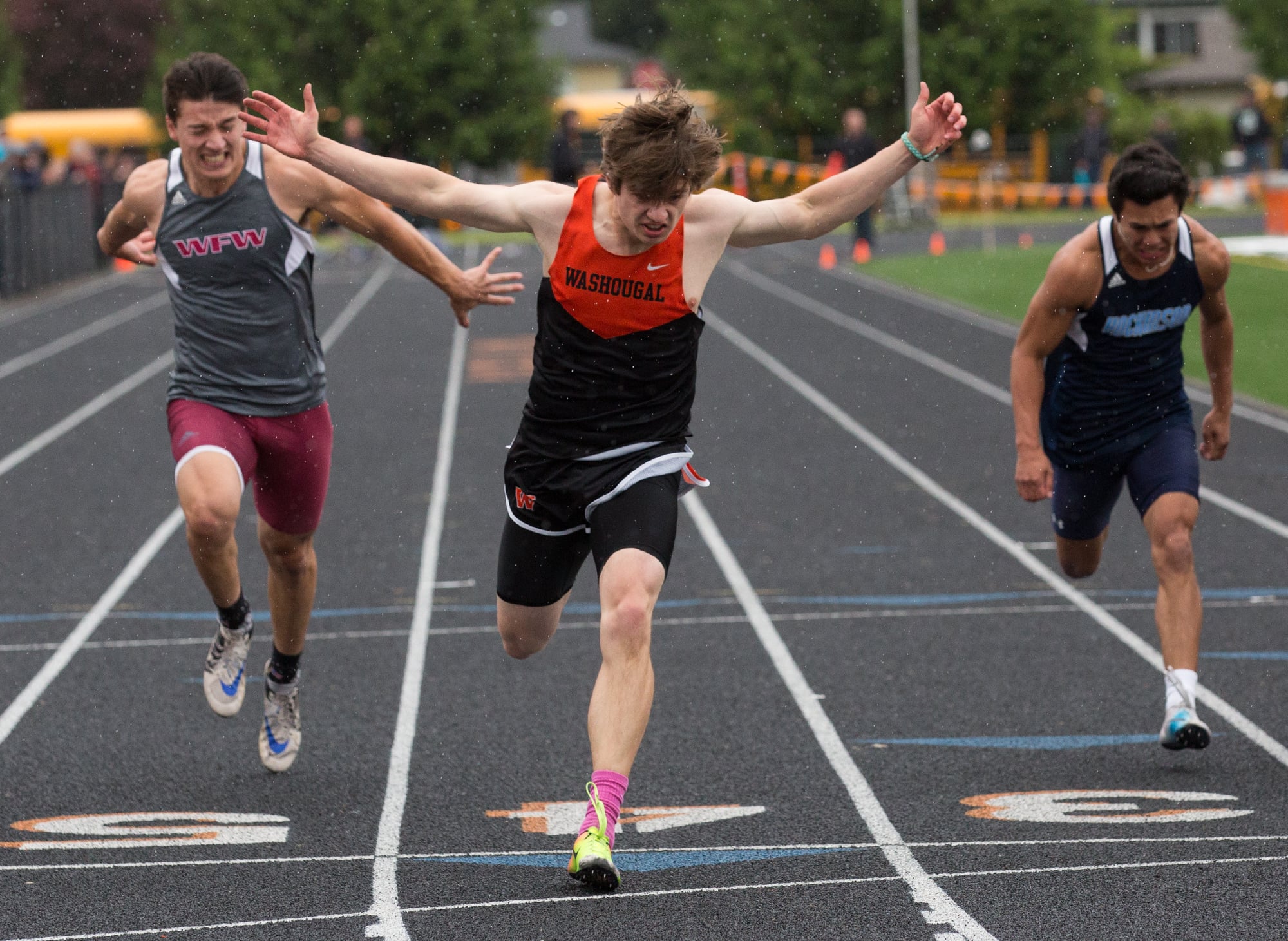 Washougal's Ryan Davy (center) stretches past the finish line as he wins the boys 100-meter run during the 2A District Track and Field Championships at Washougal High School, Friday, May 17, 2019.