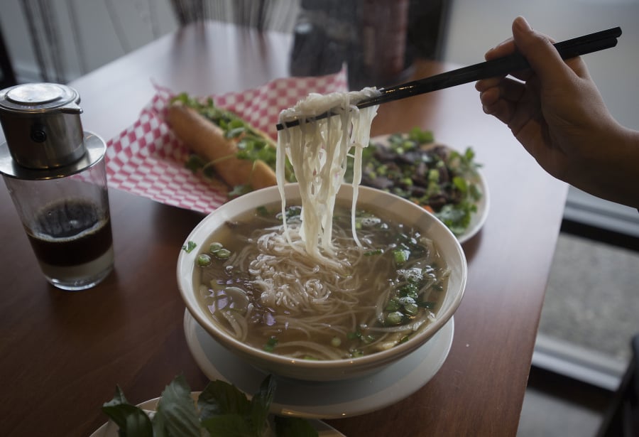 A bowl of Pho Chin Nam, clockwise from center, is served with a Vietnamese coffee with sweetened condensed milk, a grilled pork Banh Mi and beef short ribs at UnPhogettable.