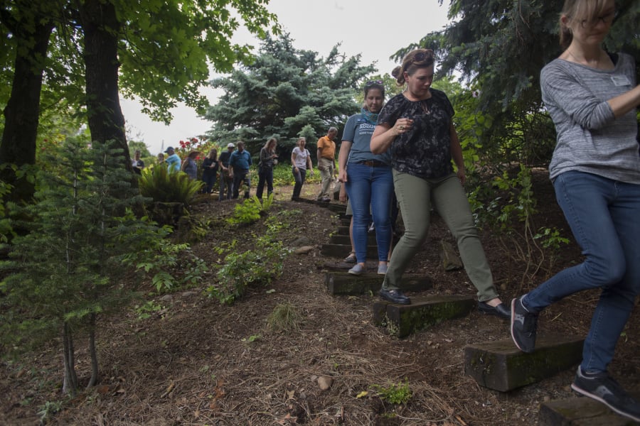 Vancouver resident Toree Hiebert, in green pants, leads a group through her backyard Wednesday afternoon before becoming the first person in Clark County to achieve silver certification under the Backyard Habitat Certification Program.