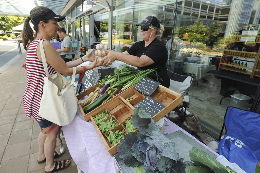 Melissa Leady, left, buys eggs from Heather Lawhead of Blue Dog Farm at the Salmon Creek Farmers’ Market at Legacy Salmon Creek Medical Center in 2016. The market is returning for its 10th year on June 11, and its eighth year at the hospital.