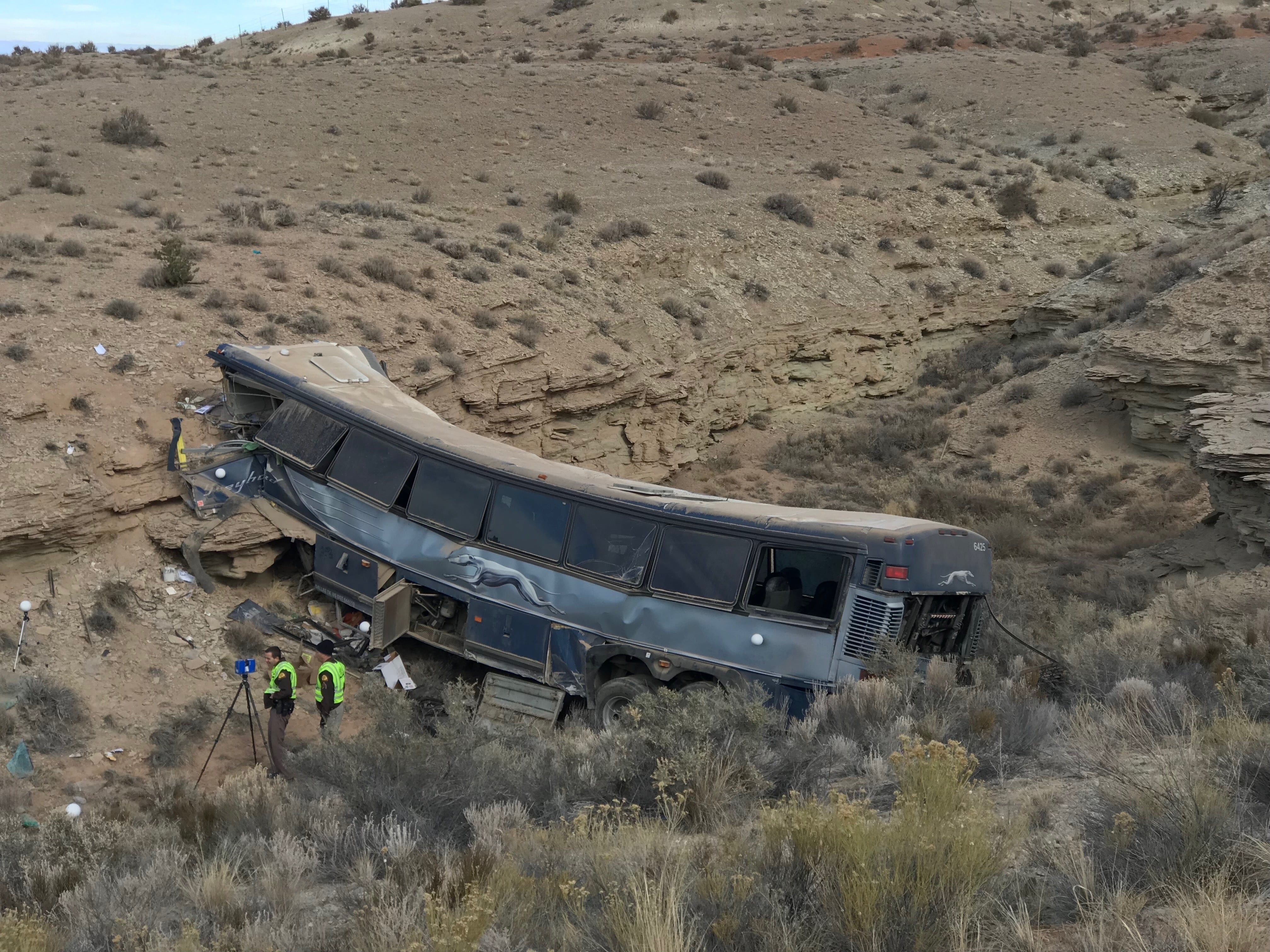 FILE - This Jan. 1, 2018, file photo, shows the aftermath of a Greyhound bus crash in Emery County, Utah. A man who suffered serious injuries when a Greyhound bus careened off a road in the Utah desert has sued the driver and the company, saying the driver was tired and sick and shouldn't have behind the wheel in a 2017 crash that killed one person and injured 12 others. Michael Edwards of Georgia says in the lawsuit filed Monday, May 13, 2019, in Nevada that Charles E. Saunders fell asleep after taking cold medicine and never hit the brakes as the bus flew off the highway and crashed into a canyon wall about 300 miles (483 kilometers) south of Salt Lake City.