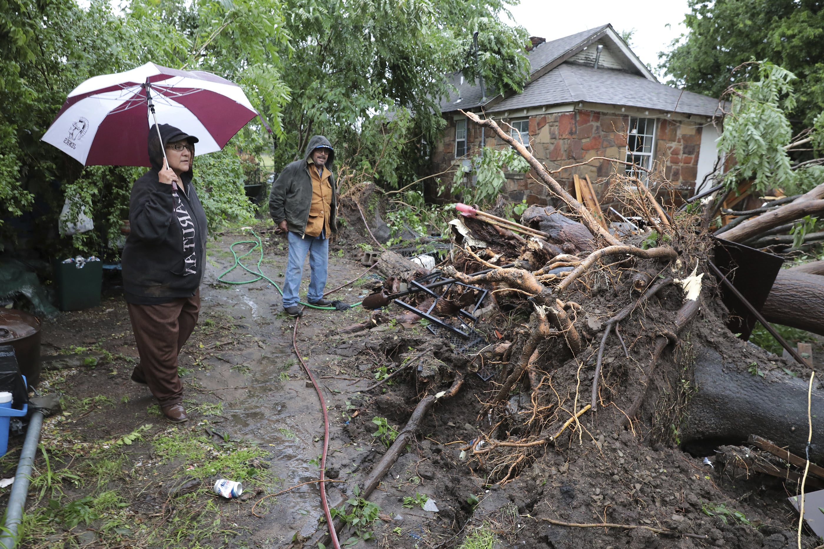Carmen Perez and Jorge Torres survey storm damage of their home near Marshall and North Rockford in Tulsa on Tuesday, May 21, 2019. Their front door was blocked by a tree and they had to get out of their home through a front window.