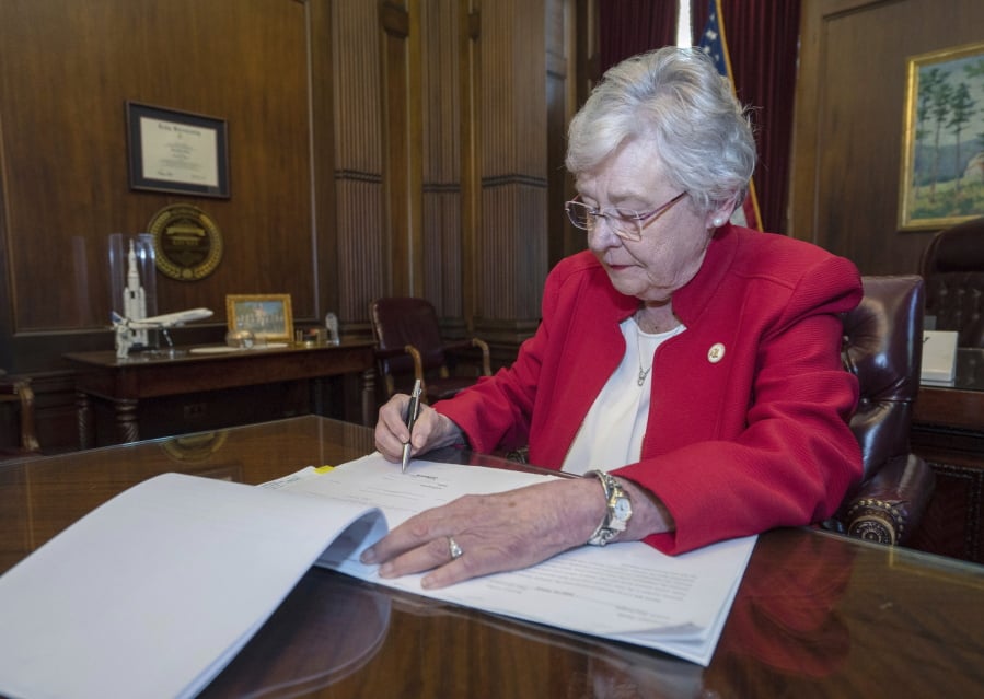 This photograph released by the state shows Alabama Gov. Kay Ivey signing a bill that virtually outlaws abortion in the state on Wednesday, May 15, 2019, in Montgomery, Ala.