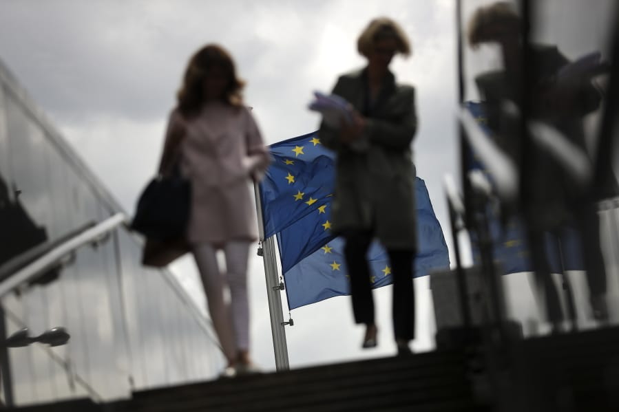 Two women walk near EU flags outside the European Commission headquarters in Brussels, Monday, May 27, 2019. Europeans woke Monday to a new political reality after European Parliament elections ended the domination of the EU’s main center-right and center-left parties and revealed a changed political landscape where the far-right, pro-business groups and environmentalists will be forces to be reckoned with.