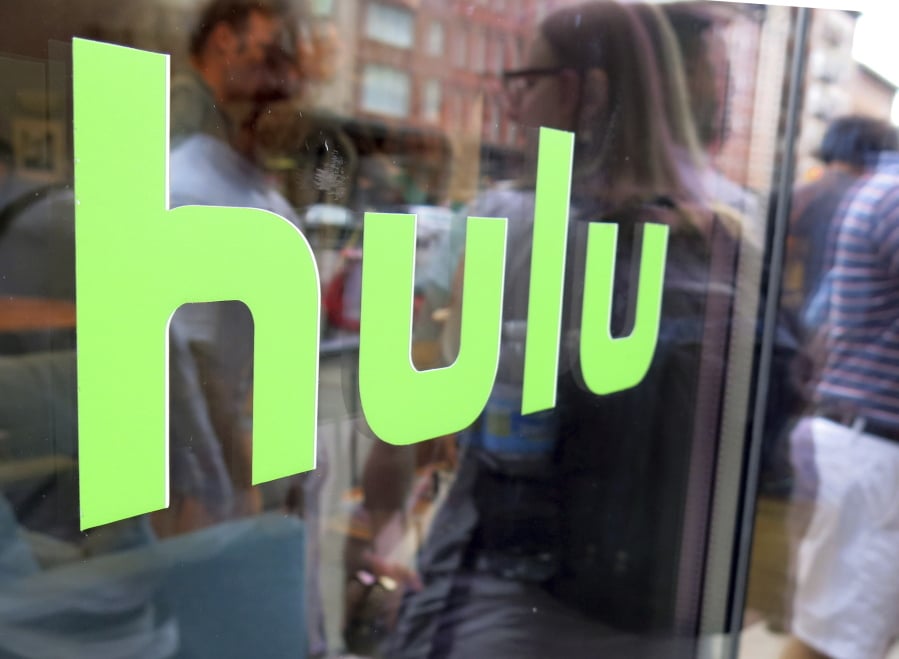 FILE - This June 27, 2015, file photo, shows the Hulu logo on a window at the Milk Studios space in New York. Disney has struck a deal with Comcast that gives it full control of streaming service Hulu. The companies said Tuesday, May 14, 2019, that as early as January 2024 Comcast can require Disney to buy NBCUniversal’s 33% interest in Hulu and Disney can require NBCUniversal to sell that stake to Disney for its fair market value at that future time.