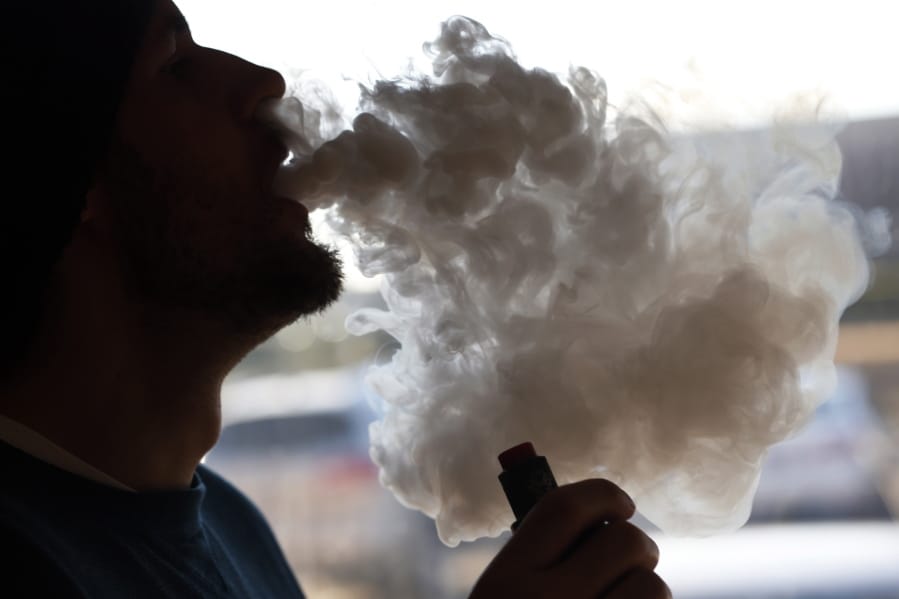 FILE - In this Friday, Jan. 18, 2019 file photo, a customer blows a cloud of smoke from a vape pipe at a local shop in Richmond, Va. Although e-cigarettes aren’t considered as risky as regular cigarettes, new research published Monday, May 27, 2019, finds a clue that their flavorings may be bad for the heart.