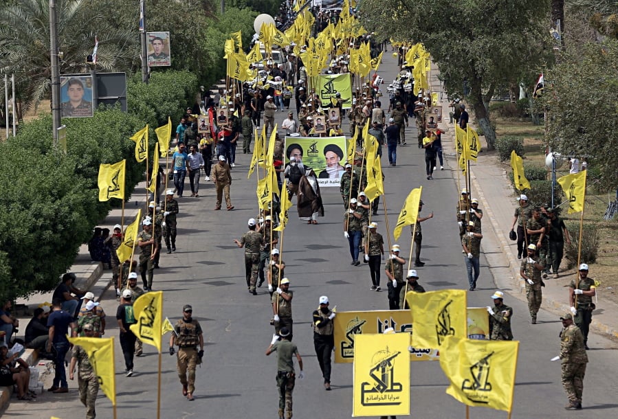 Iraqi Popular Mobilization Forces march on June 8, 2018, holding their flag and posters of Iraqi and Iranian Shiites spiritual leaders during “al-Quds” or Jerusalem Day in Baghdad, Iraq.