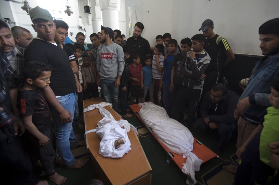 Palestinians stand around the bodies of a four-months-old girl Maria Al-Ghazali, her father Ahmad and mother Iman Al-Ghazali, laid inside a coffin, who were killed in a late Sunday Israeli missile strike during their funeral in town of Beit Lahiya, northern Gaza Strip, Monday, May. 6, 2019.