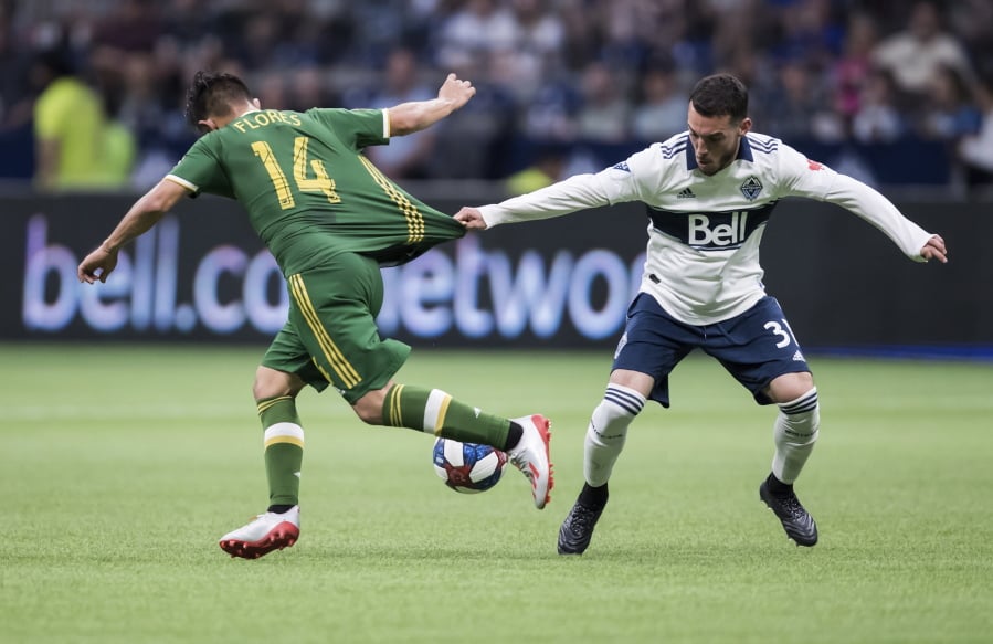 Vancouver Whitecaps’ Russell Teibert, right, grabs the jersey of Portland Timbers’ Andres Flores as he tries to slow Flores down during the second half of an MLS soccer match Friday, May 10, 2019, in Vancouver, British Columbia.