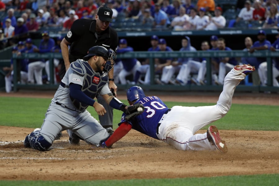 Seattle Mariners catcher Omar Narvaez (22) attempts the tag as Texas Rangers’ Nomar Mazara (30) scores on a sacrifice fly by Asdrubal Cabrera in the fourth inning of a baseball game in Arlington, Texas, Tuesday, May 21, 2019. Umpire Andy Fletcher watches the play develop.