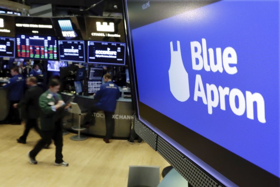 FILE - In this Thursday, Oct. 19, 2017, file photo, the logo for Blue Apron appears on a screen above the trading floor of the New York Stock Exchange. Meal kit companies face an ultimatum: Adapt or die. The struggle has intensified for Blue Apron, which announced that it could be delisted from the New York Stock Exchange because its closing share price has been lower than $1 since early May 2019.
