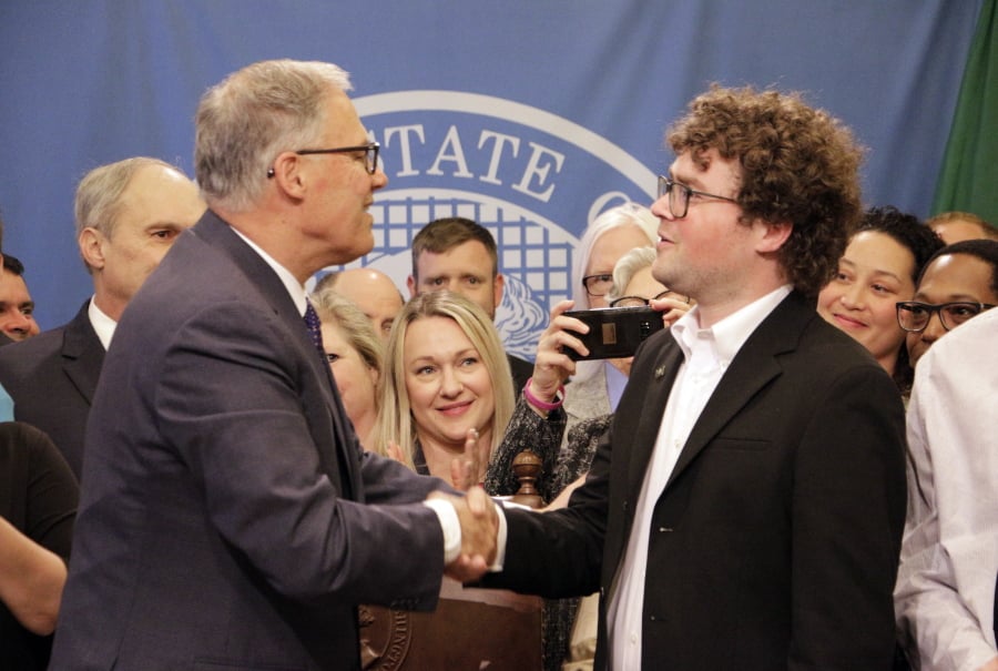 Gov. Jay Inslee shakes hands with Joshua Stuller after deeming him “Washingtonian of the Day” following the signing of a bill that seeks to speed up competency evaluations for defendants at jails, on Thursday, May 9, 2019, in Olympia, Wash. Stuller, who advocated for the legislation, was released from Eastern State Hospital last year.