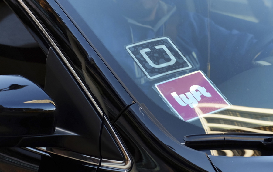 FILE - In this Jan. 12, 2016, file photo, a ride share car displays Lyft and Uber stickers on its front windshield in downtown Los Angeles. One in six Uber and Lyft drivers in the New York City and Seattle areas are driving vehicles with outstanding recalls, according to Consumer Reports. But taking a taxi or limousine isn’t necessarily a safer option as nearly a quarter of traditional for-hire vehicles in New York City also have outstanding recalls, Consumer Reports said.