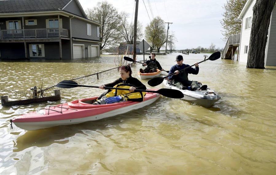In this Wednesday, May 8, 2019 photo, Estral Beach Firefighters Courtney Millar, Eric Bruley, and Chase Baldwin kayak down Lakeshore Dr. in the south end of Estral Beach in Berlin Township, Mich., to see if anyone needs to be evacuated while also checking the floodwaters. Wind-driven water caused more flooding in southeastern Michigan along western Lake Erie following recent rainfall that contributed to high water levels in the Great Lakes .