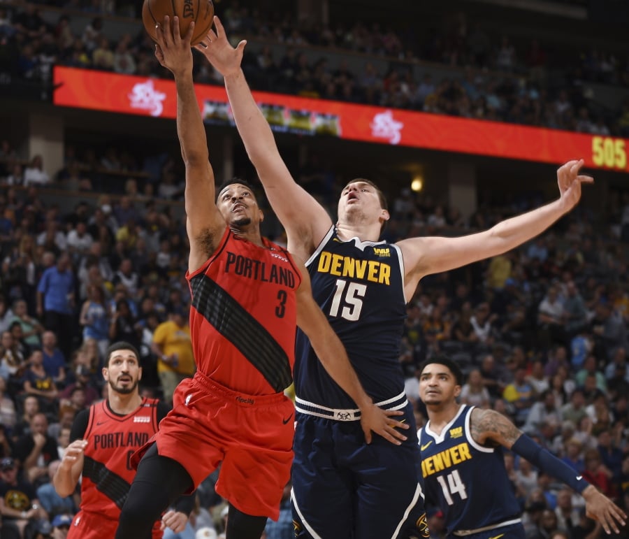 Portland Trail Blazers guard CJ McCollum, front left, drives to the rim past Denver Nuggets center Nikola Jokic in the second half of Game 7 of an NBA basketball second-round playoff series Sunday, May 12, 2019, in Denver.
