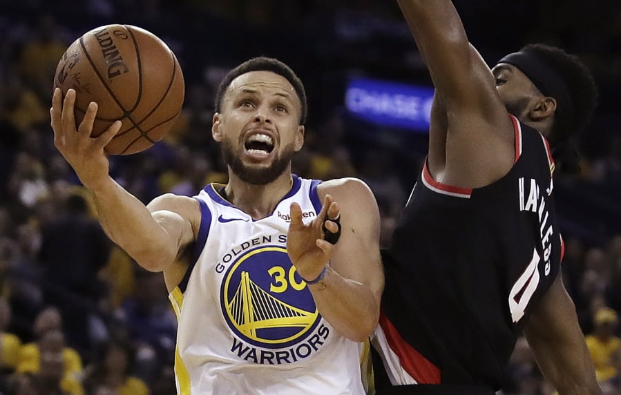 Golden State Warriors' Stephen Curry, left, lays up a shot past Portland Trail Blazers' Maurice Harkless during the first half of Game 1 of the NBA basketball playoffs Western Conference finals Tuesday, May 14, 2019, in Oakland, Calif.
