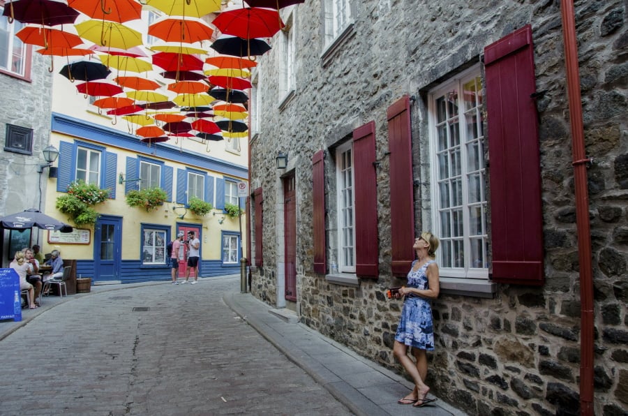 Paule Bergeron takes in the scene in Place-Royale in Old Quebec, Aug. 27, 2018. Quebec City offers compelling urban bike routes along the river, out to Montmorency Falls and through intriguing neighborhoods, as well as access to the Jacques-Cartier rail trail running through forest, farmland and meadows.