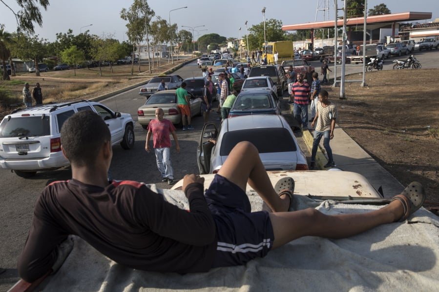 People line the street with their vehicles as they wait to fill up with gas at a fuel station Wednesday in Cabimas, Venezuela. U.S. sanctions on oil-rich Venezuela appear to be taking hold, resulting in mile-long lines for fuel in the South American nation’s second-largest city, Maracaibo.