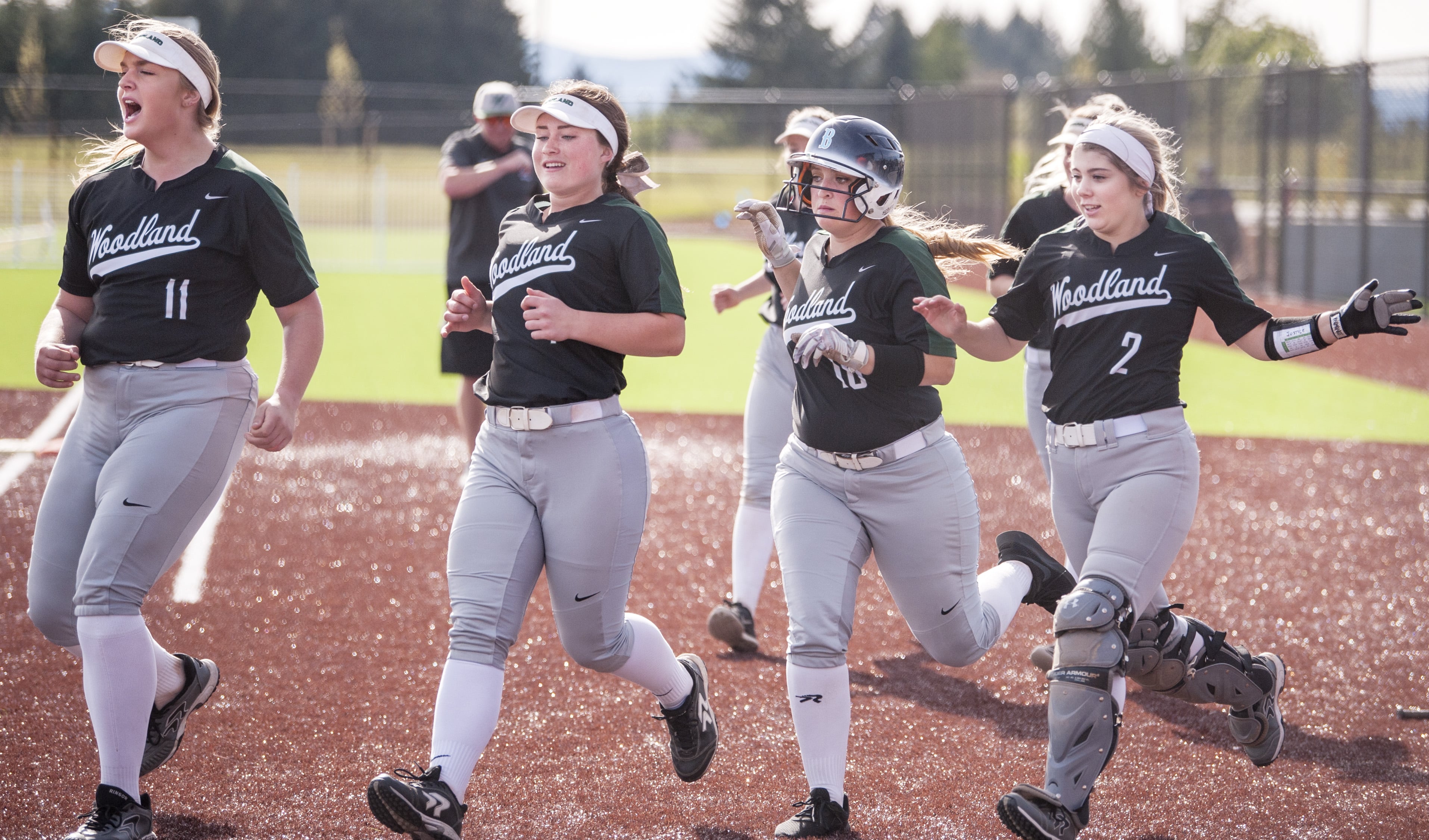 From left to right, Woodland's Olivia Grey, Kailey Christensen, Carleigh Risley and Justice Holcomb run to celebrate Payten Foster's two-run home run Friday at the Ridgefield Outdoor Recreation Complex.