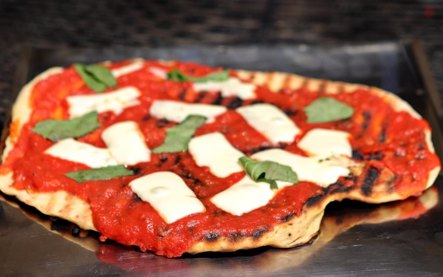Make your own pizza on the barbecue grill, shown here with basil and mozzarella. (Hillary Levin/St.