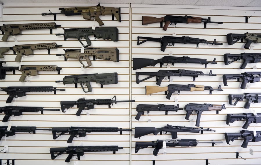 Semi-automatic rifles fill a wall in October at a gun shop in Lynnwood. On Monday, much of Initiative 1639 will go into effect: People wanting to purchase semi-automatic assault rifles will have to undergo an enhanced background check, prove that they’ve undergone firearms safety training and could face criminal liability for not securing firearms.