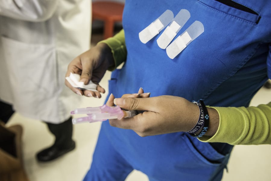 A certified medical assistant holds needles full of the HPV vaccination drug Gardasil before administering them to children at a community health center in Texas.