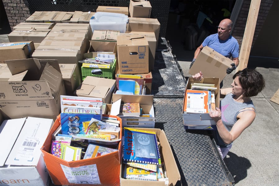 Jennifer Scott and her husband, Kevin Scott, load boxes of donated books onto a flatbed truck at their Camas home before moving the books to the Camas School District offices.