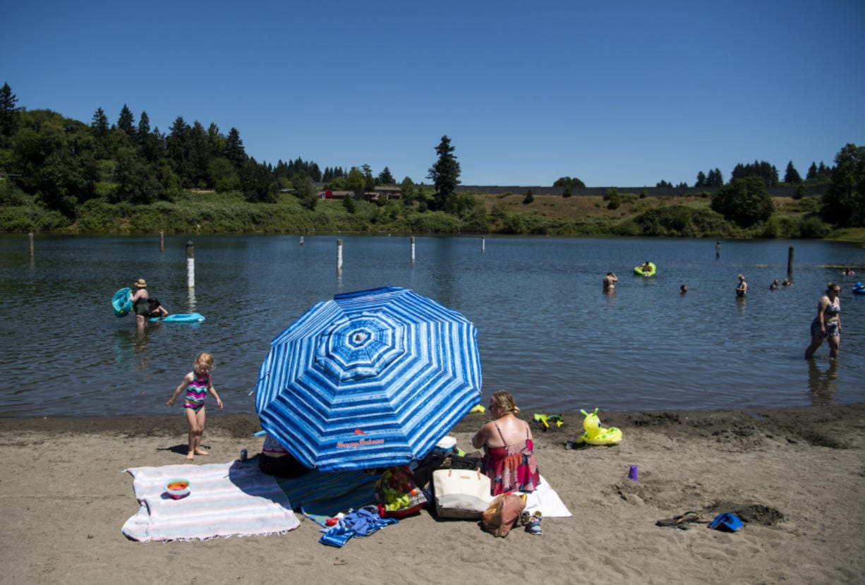 People scatter about the beach Tuesday afternoon at Klineline Pond as temperatures hit 95 degrees in Vancouver.