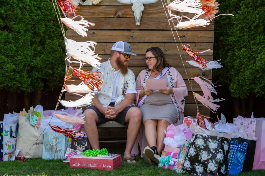 Lance and Kayla Edwards exchange a glance while opening gifts at their baby shower in Vancouver. Edwards was born without a uterus, cervix or fallopian tubes, but a uterine transplant in 2017 gave her the ability to give birth. At top, Kayla Edwards is surrounded by friends and family at her baby shower in Vancouver.
