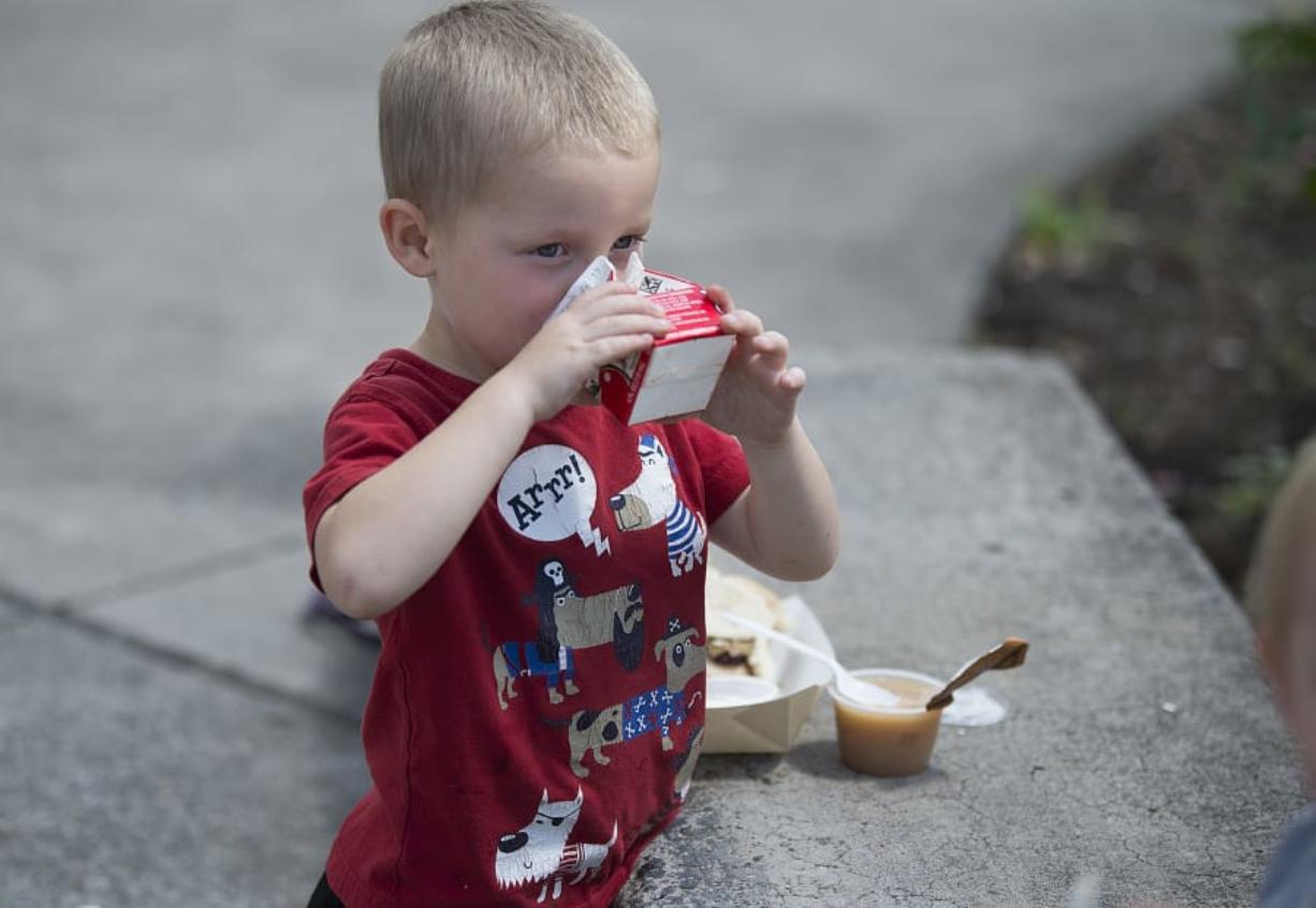 Hunter Randolph, 4, washes down his lunch with a carton of apple juice Friday at Kiwanis Community Park in Battle Ground.