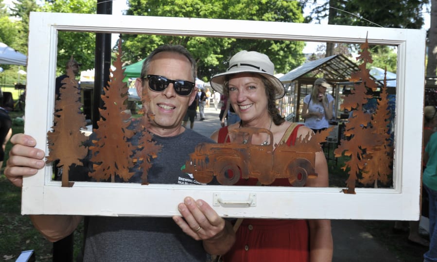 Dan Colwell, left, and Lorraine Colwell show off their purchase Sunday as they leave the annual Clark County Recycled Arts Festival at Esther Short Park in Vancouver.