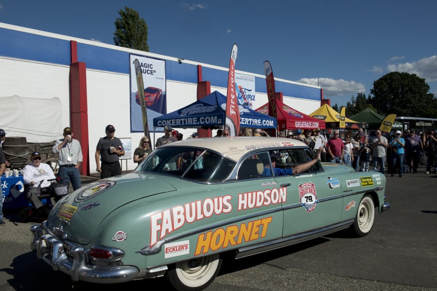 Jesse Jameson, owner and navigator of a 1952 Hudson Hornet, waves to spectators as the car arrives Friday evening at the Western Antique Aeroplane & Automobile Museum in Hazel Dell. Jameson was one of more than 100 participants in The Great Race, a nine-day road rally that focuses on time instead of speed. At top, the clock, radio mic and covered speedometer are essential tools of the rally racer, seen Friday during The Great Race’s stop in Vancouver.